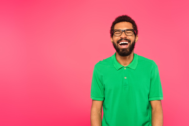 Αφροαμερικάνος με γυαλιά γελώντας απομονωμένος στο ροζ. - Φωτογραφία, εικόνα