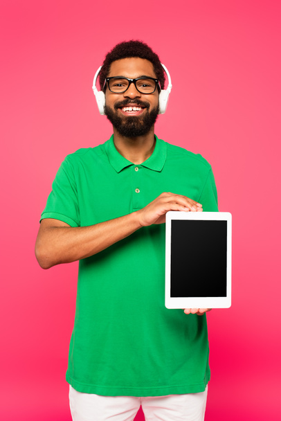 cheerful african american man in glasses and headphones holding digital tablet with blank screen isolated on pink - Fotografie, Obrázek
