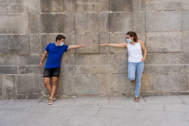 Man and woman wearing protective face masks standing 2 m from each other keeping social distancing avoiding the spread of coronavirus. Conceptual image of COVID-19 disease protection and New Normal. - Φωτογραφία, εικόνα