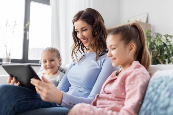 happy mother and daughters with tablet pc at home - Photo, image