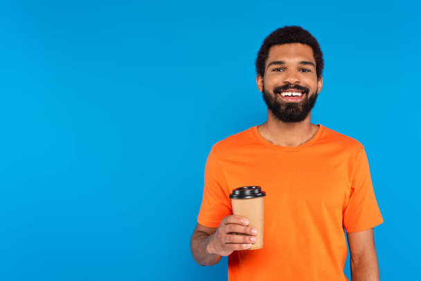 happy african american man holding paper cup isolated on blue - Photo, Image
