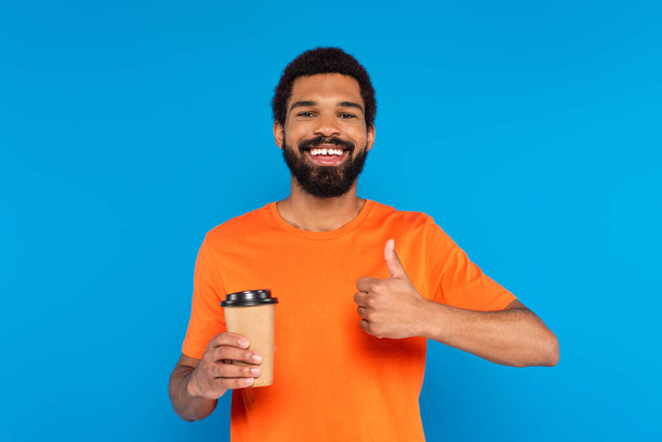happy african american man showing thumb up and holding paper cup isolated on blue - Φωτογραφία, εικόνα
