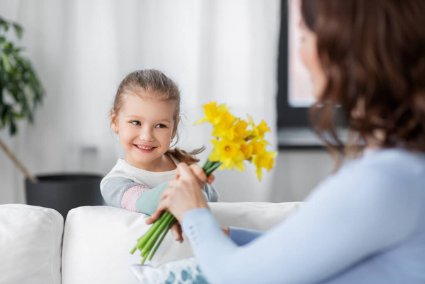 happy daughter giving daffodil flowers to mother - Photo, Image