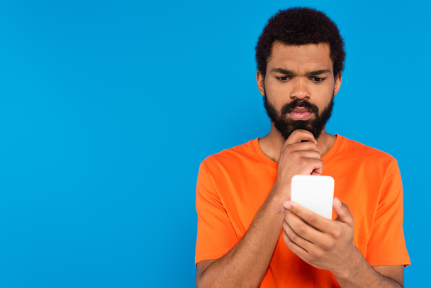 thoughtful african american man using smartphone isolated on blue - Fotoğraf, Görsel
