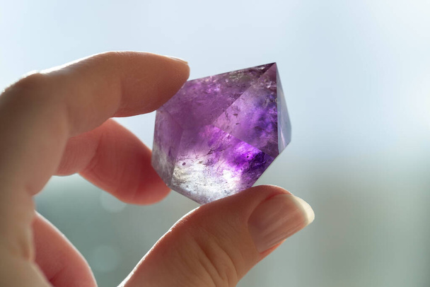 Amethyst Kristall in der Hand. Lila transluzente Kristall-Nahaufnahme - Foto, Bild