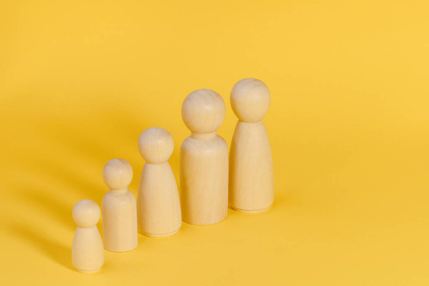 Öt tagú család, sárga hátterű fából készült figurákból. Család sok gyermekkel, több gyermekkel vagy több tagú családdal. - Fotó, kép