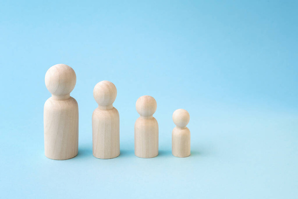 Wooden figurines standing in line from high to low on blue background. Family members or personal - Photo, Image