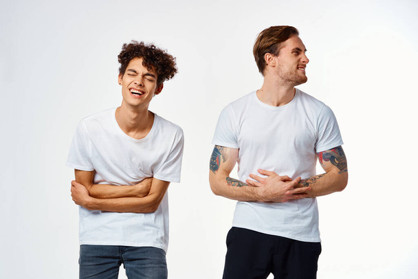 двоє чоловіків у білих футболках стоять поруч з емоціями дружби
 - Фото, зображення