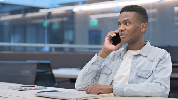 Afrikai férfi beszél okostelefonon az irodában  - Fotó, kép
