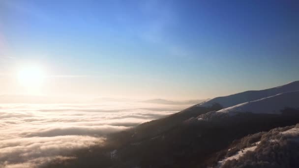 Воздушный кадр величественного восхода солнца в горах. Долина между горами покрыта туманом и освещена теплыми лучами восходящего солнца. Горы, покрытые лесом. - Кадры, видео
