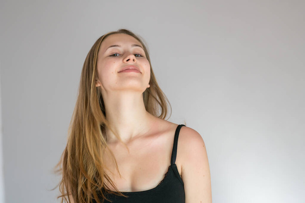 Studioporträt einer jungen blonden Frau, die lächelnd ihren Hals zeigt - Foto, Bild