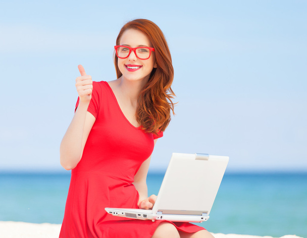 Рыжая девушка в очках с блокнотом на пляже
 - Фото, изображение