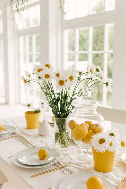 Kauniisti palvellut kevät kesä valkoinen pöytä, jossa on paljon sitruunoita ja kamomilla. - Valokuva, kuva