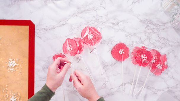 Flat lay. Wrapping large homemade lollipops into clear gift bags. - Photo, Image
