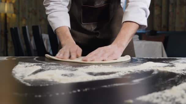 Séf alkotó tészta pizza és gyúró kézzel, a hagyományos pizzéria konyhában. Közelről. Pizzát készítek az asztalon. Lassú mozgás. Teljes hd - Felvétel, videó