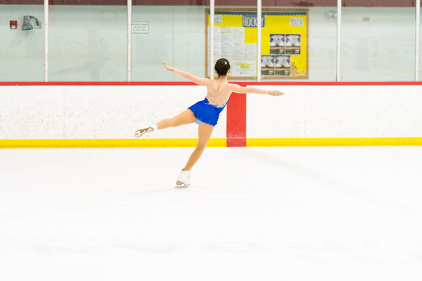 Teenage girl practicing figure skating on an indoor ice skating rink. - Fotoğraf, Görsel