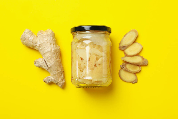 Pot avec gingembre mariné et gingembre sur fond jaune - Photo, image