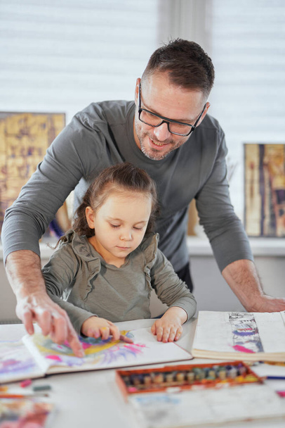 Fürsorglicher Vater hilft Tochter beim Malen mit Bleistiften - Foto, Bild