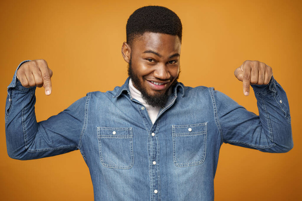 Young african american man pointing down and smiling, yellow background - Foto, afbeelding