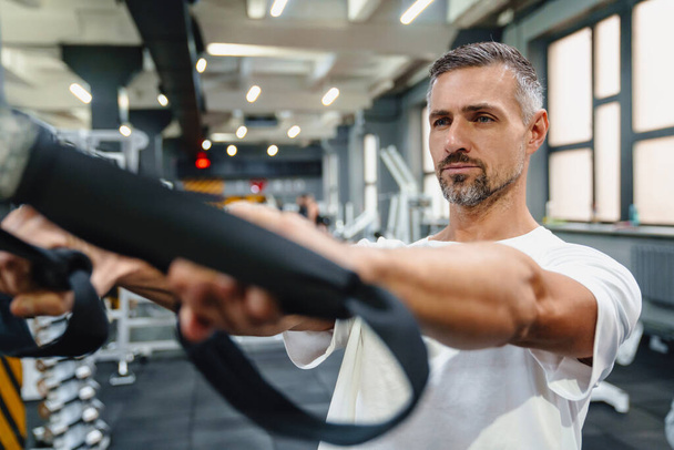 Attractive confident healthy sports man using seated lat pulldown machine in the gym - Φωτογραφία, εικόνα