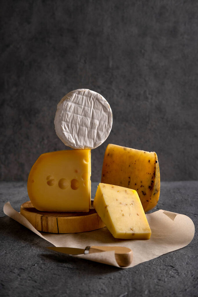 Various types of cheese on grey board. Dark moody. Free space for your text. Closeup. - Photo, Image
