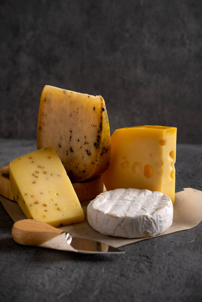 Various types of cheese on grey board. Dark moody. Free space for your text. Closeup. - Zdjęcie, obraz