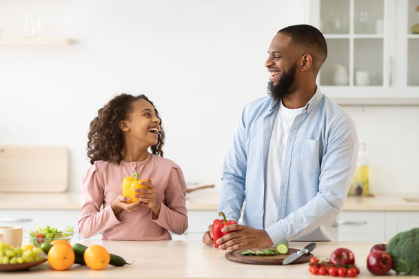 Cheerful african father and daughter cooking healthy salad - Photo, Image