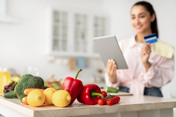 Mujer de compras en línea con tableta y tarjeta de crédito en la cocina - Foto, imagen