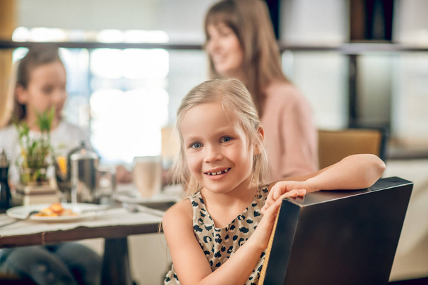 Sweet girl sitting at the table in the restaurant with family - Fotó, kép