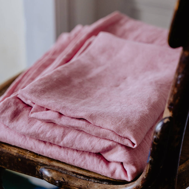 A selective focus shot of folded pink bedding on the old wooden chair - Фото, зображення
