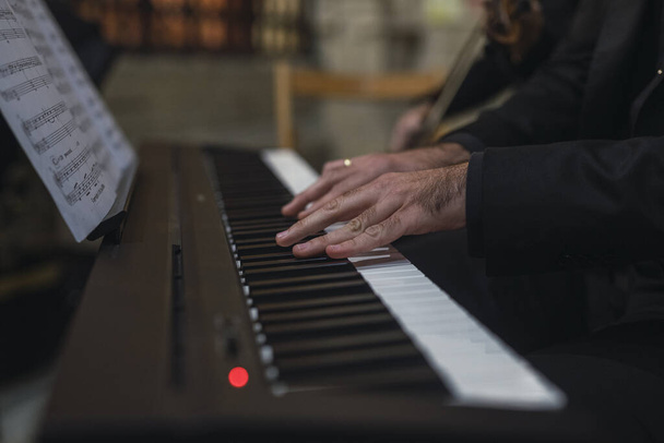 A closeup shot of a man playing piano on a blurred background - Фото, зображення