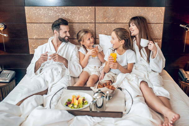 Family having breakfast in bed and enjoying it - Foto, afbeelding