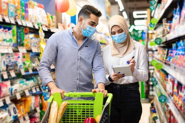 Muslim Couple Taking Notes In List Buying Food In Supermarket - Photo, Image