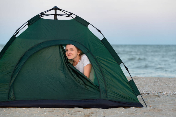 Młoda blondynka turystka wychodząca z namiotu. Kemping nad morzem - Zdjęcie, obraz
