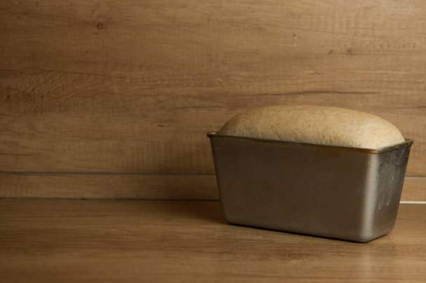 Zelfgebakken geroosterd volkoren brood en metalen vorm voor brood op houten tafel. Kopieerruimte - Foto, afbeelding