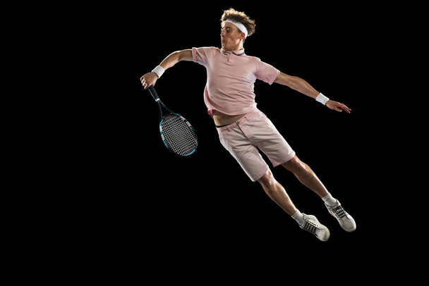 Młody biały mężczyzna, profesjonalny tenisista odizolowany na czarnym tle. - Zdjęcie, obraz