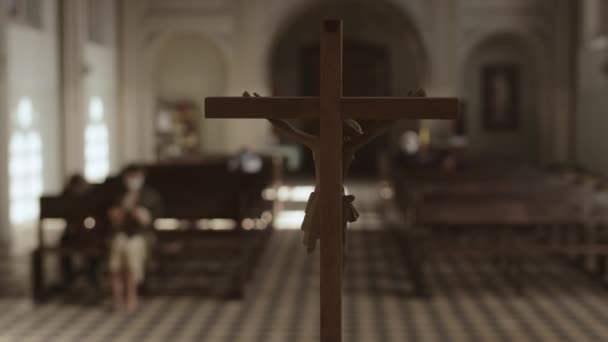 Achteraanzicht van het houten kruisbeeld van Jezus Christus in de Lutherse kerk en verschillende onherkenbare parochianen op kerkbanken - Video