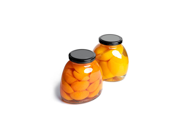 Абрикосы и персики в стеклянной банке. Сладкие абрикосы и персики в сиропе изолированы на белом фоне. - Фото, изображение