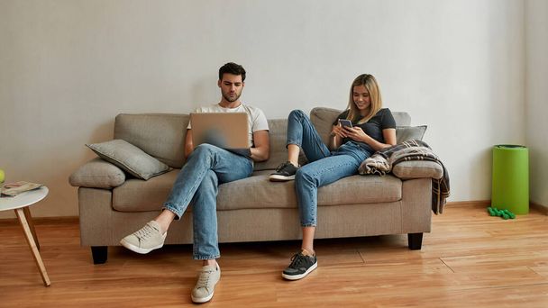 Young man and woman relaxing on the couch and surfing the net  - Foto, Imagen
