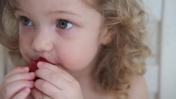 Neljä tonnia. Curly kaunis vauva tyttö syö omena vaalean harmaa tausta - Materiaali, video