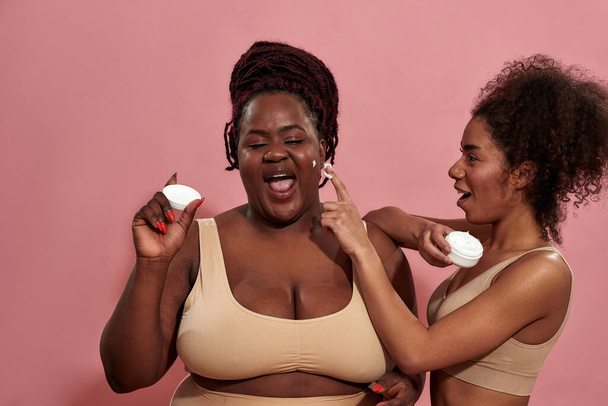 Couple of young women having fun with cosmetic cream - Foto, imagen