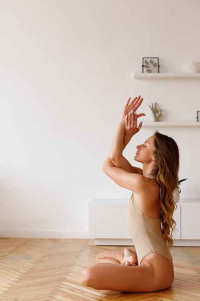 Mulher em bodysuit em asana lótus ioga pose em casa - Foto, Imagem