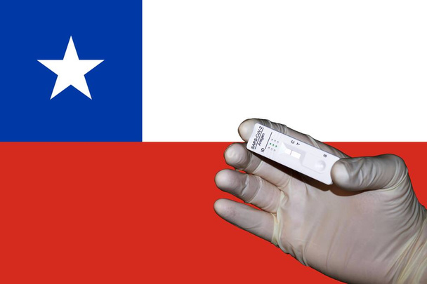 Eine Hand mit einem negativen antigenen Corona-Schnelltest vor einer chilenischen Flagge - Foto, Bild