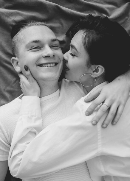 couple at home in home clothes lie on the bed and hug each other black and white photo - Фото, изображение