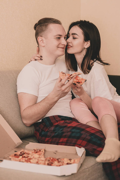カップルでホーム服に家でベッド食べるピザ - 写真・画像