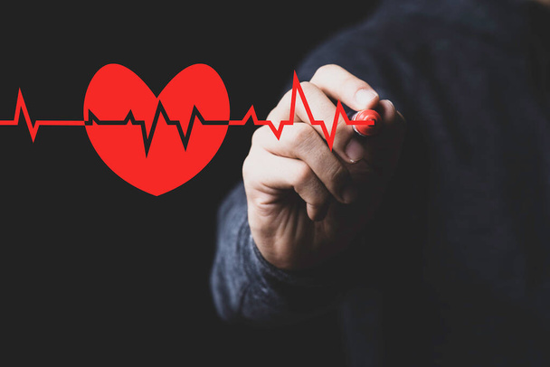 Hombre mano dibujo signo de onda con corazón rojo sobre fondo negro, sano y el concepto de enfermedades del corazón. - Foto, imagen