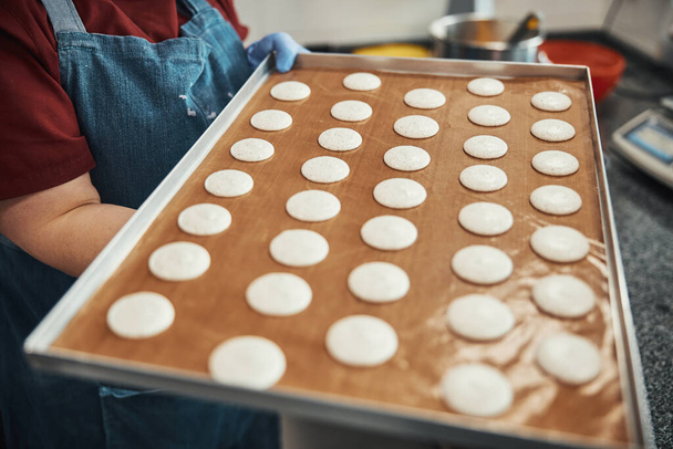 Talented cook carrying tray with macaron batter dots - Photo, Image