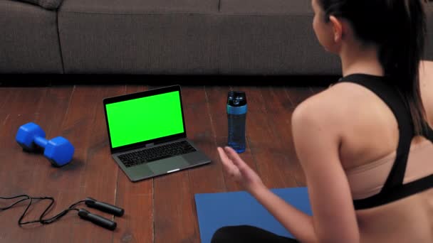 Groen scherm laptop concept: Atletische vrouw in sportkleding zit op yoga mat - Video