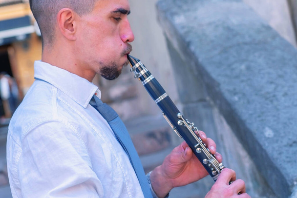 Profile portrait of funny image of male musician music with clarinet outdoors in old European city.  - Photo, Image