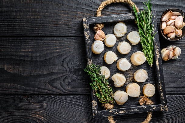 Fresh scallops meat in a wooden tray. Black wooden background. Top view. Copy space - Foto, imagen